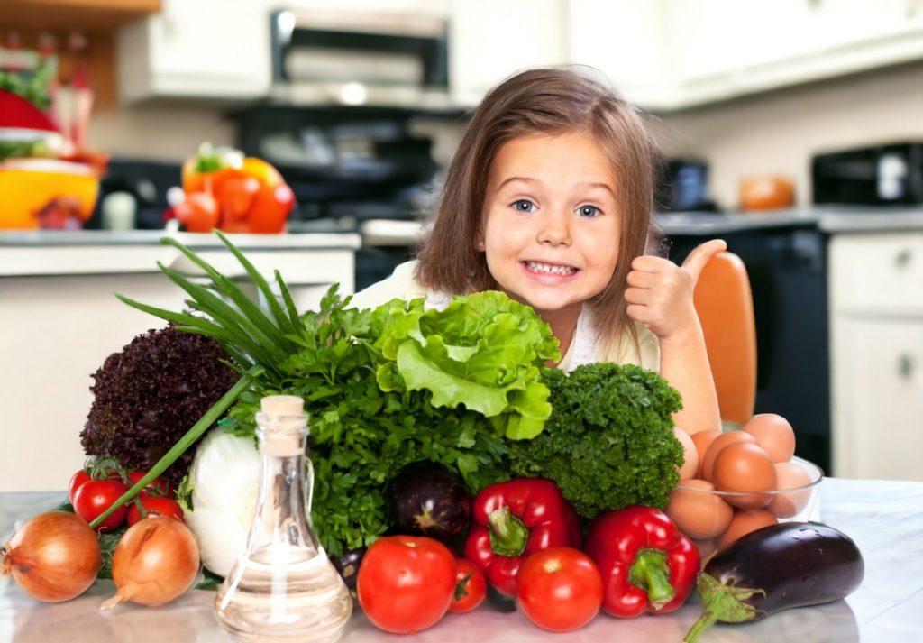 bella ragazza con verdure colorate che mostrano i pollici in su